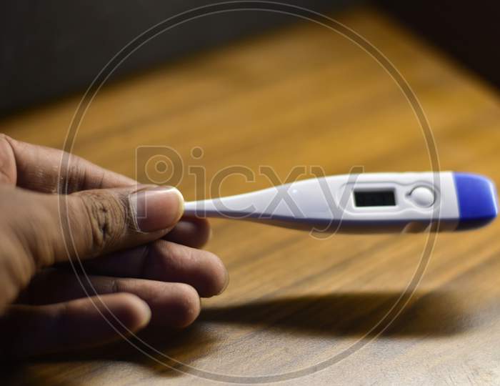 white thermometer in a man's hand with a wooden background