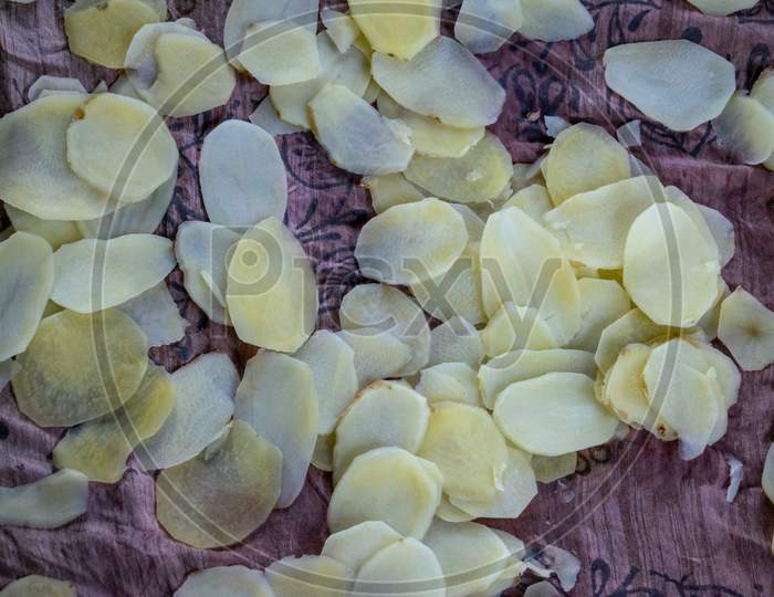 Raw potato slices are being dried during sunny day to prepare potato chips