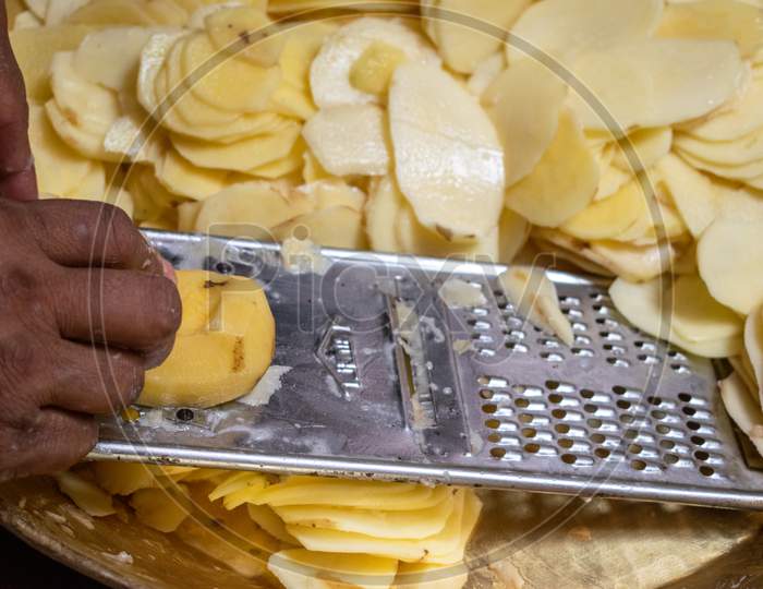 Potato slices are being cut using chips slicer to prepare potato chips