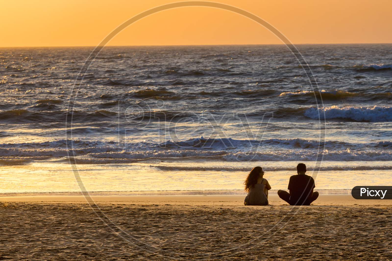 A Couple Enjoying Solitude And Beach Views  At a Sunset