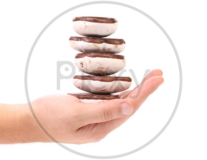 Hand Holds Stack Of Chocolate Meringues. Isolated On A White Background.
