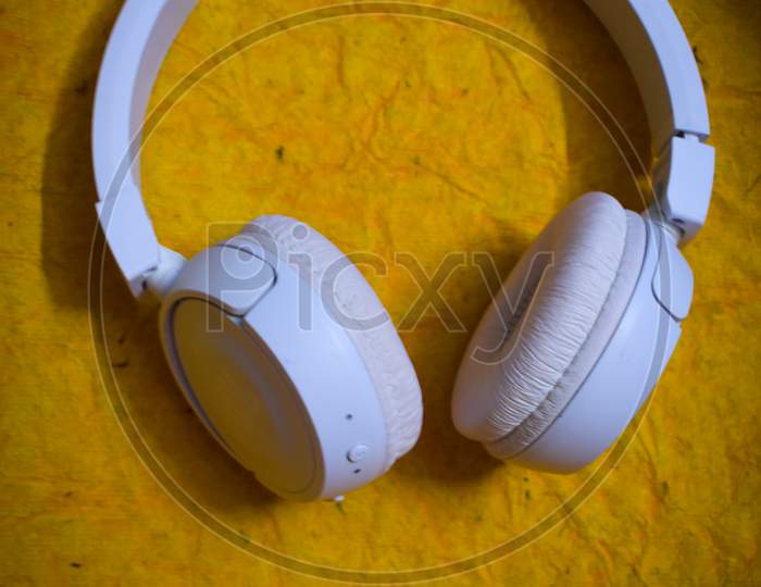 white Bluetooth headphone on a yellow background
