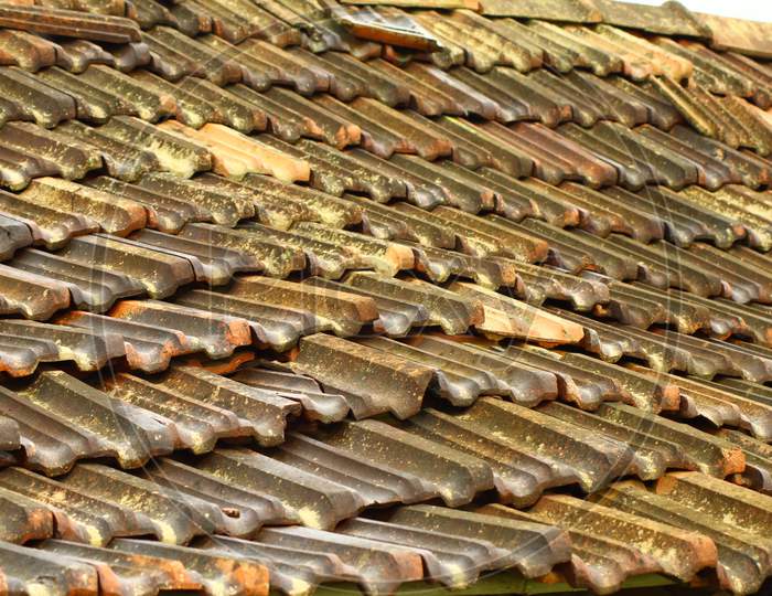 a close up of rustic Mangalore tile sloping roof with moss