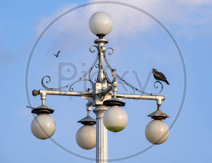The isolated vintage lamp on an iron column against the blue sky