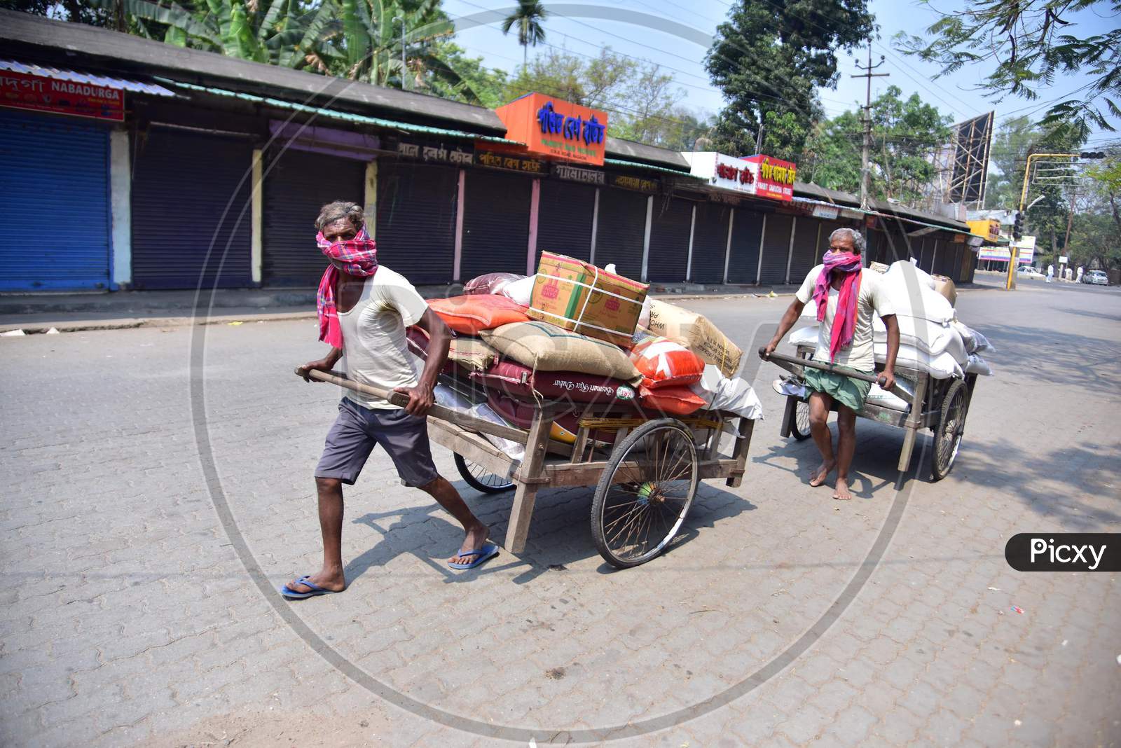 Workers  Push A Cart With  Groceries During A Nationwide Lockdown In The Wake Of Coronavirus Pandemic, In Nagaon District Of Assam ,India
