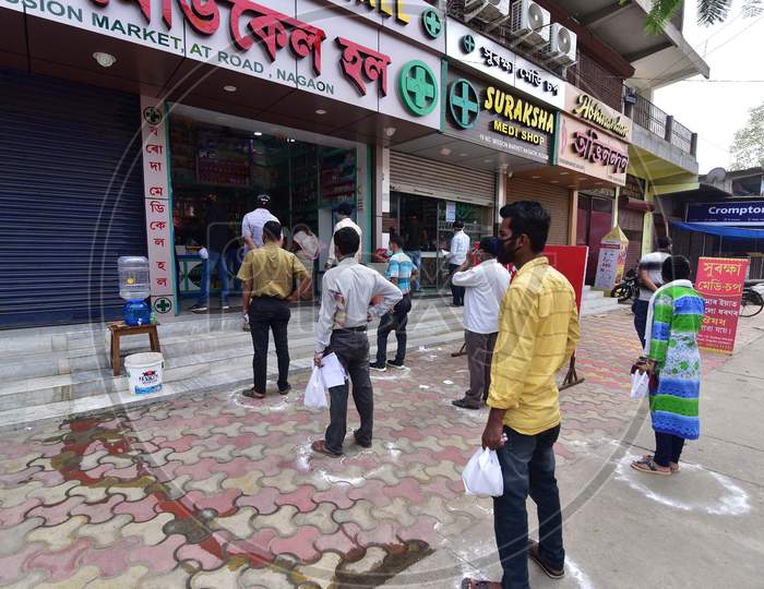 People Standing In Circles Drawn With Chalk To Maintain Safe Distance As They Wait To Enter A Medical  Shop During The Coronavirus Disease (Covid-19) Outbreak In Nagaon District Of Assam ,India