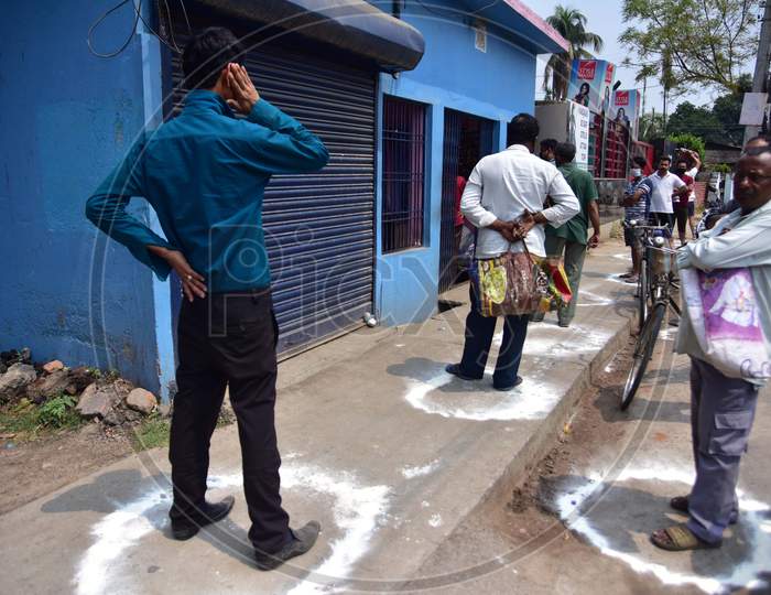 People Standing In Circles Drawn With Chalk To Maintain Safe Distance As They Wait To Enter A Shop During The Coronavirus Disease (Covid-19) Outbreak In Nagaon District Of Assam On Mar 26,2020