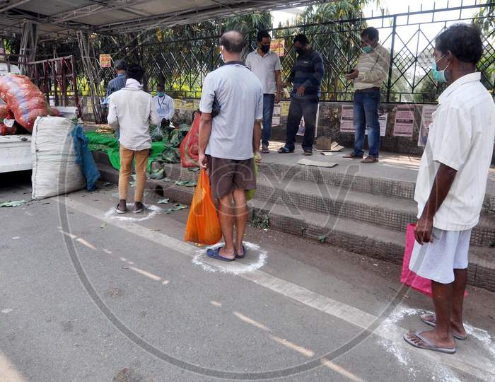 Locals Maintain Social Distance As They Stand In A Queue To Buy Vegetables, Supplied By The State Food Supply Department, During 4 Day Of Complete Lockdown In The Wake Of The Corona Virus Pandemic In Guwahati On Saturday, 28 March 2020.