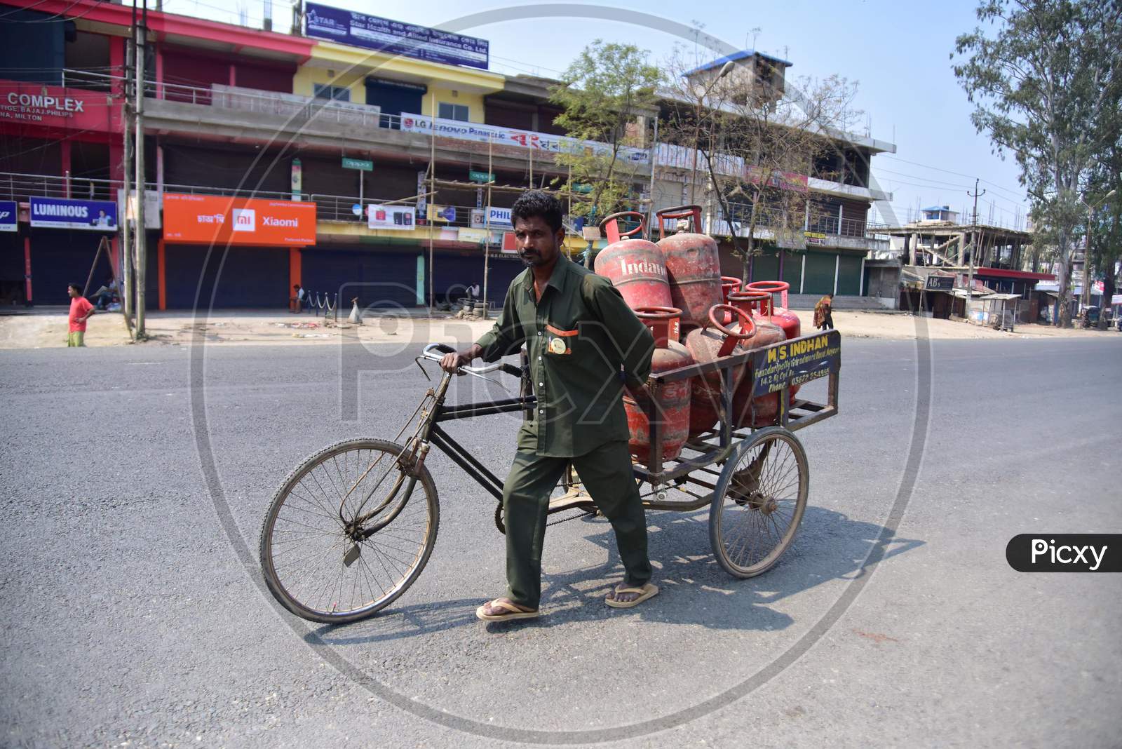 A Workers Wearing Protective Masks Push A Cart With Lpg Cylinders During A Nationwide Lockdown In The Wake Of Coronavirus Pandemic, In Nagaon District Of Assam,India