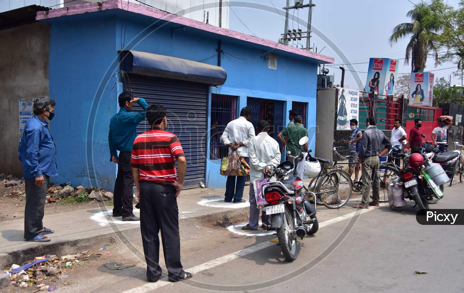 People Standing In Circles Drawn With Chalk To Maintain Safe Distance As They Wait To Enter A Shop During The Coronavirus Disease (Covid-19) Outbreak In Nagaon District Of Assam On Mar 26,2020
