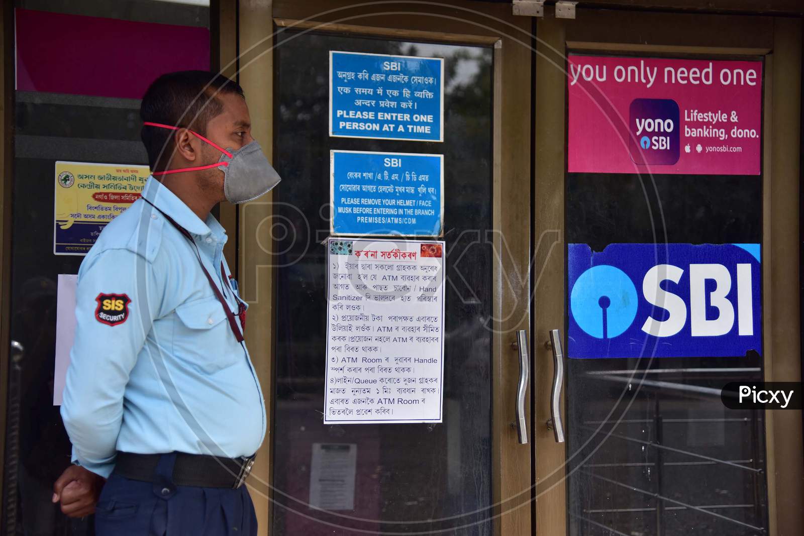 A Security Guard Wear Mask As He  Stand Outside A Bank Atm During A Nationwide Lockdown In The Wake Of Coronavirus Pandemic, In Nagaon District Of Assam On Mar 26,2020.
