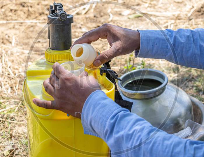 A farmer putting pesticides into pesticide sprayer