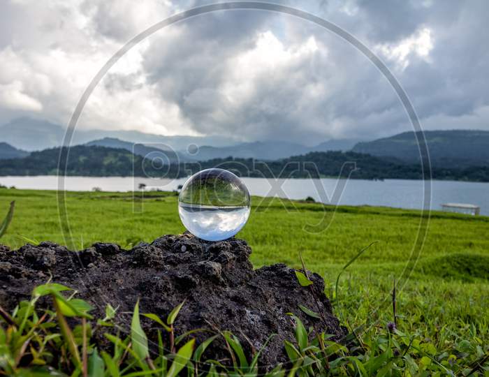 Lens ball Kept On Rock With Lake And Hills In Background Shot At BHANDARDARA