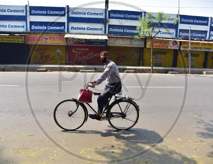 A Man Wearing A Mask Rides A Bicycle  Past Near A Closed Market  During The Nationwide Lockdown In The Wake Of Coronavirus Pandemic In Nagaon District Of Assam,India