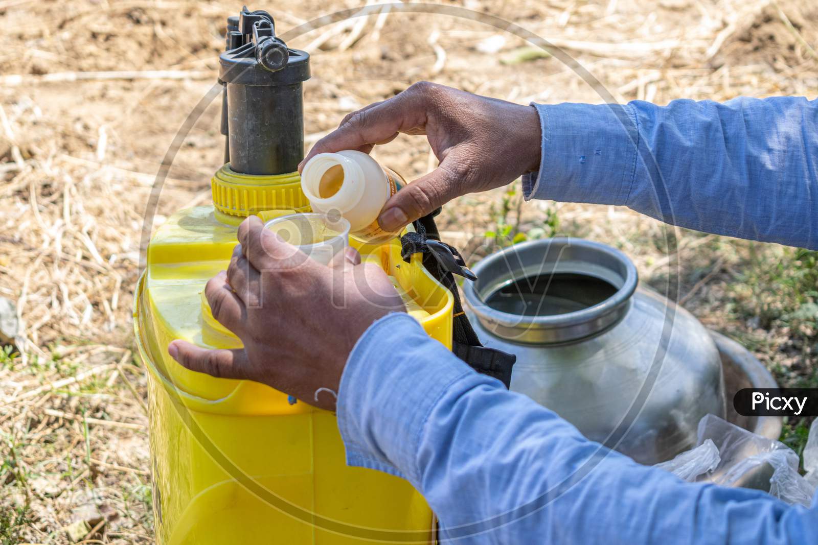 A farmer putting pesticides into pesticide sprayer