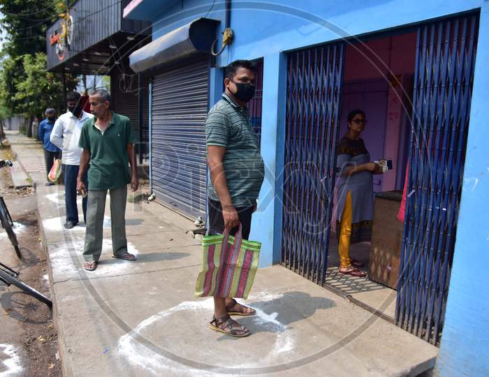People Standing In Circles Drawn With Chalk To Maintain Safe Distance As They Wait To Enter A Shop During The Coronavirus Disease (Covid-19) Outbreak In Nagaon District Of Assam On Mar 26,2020.