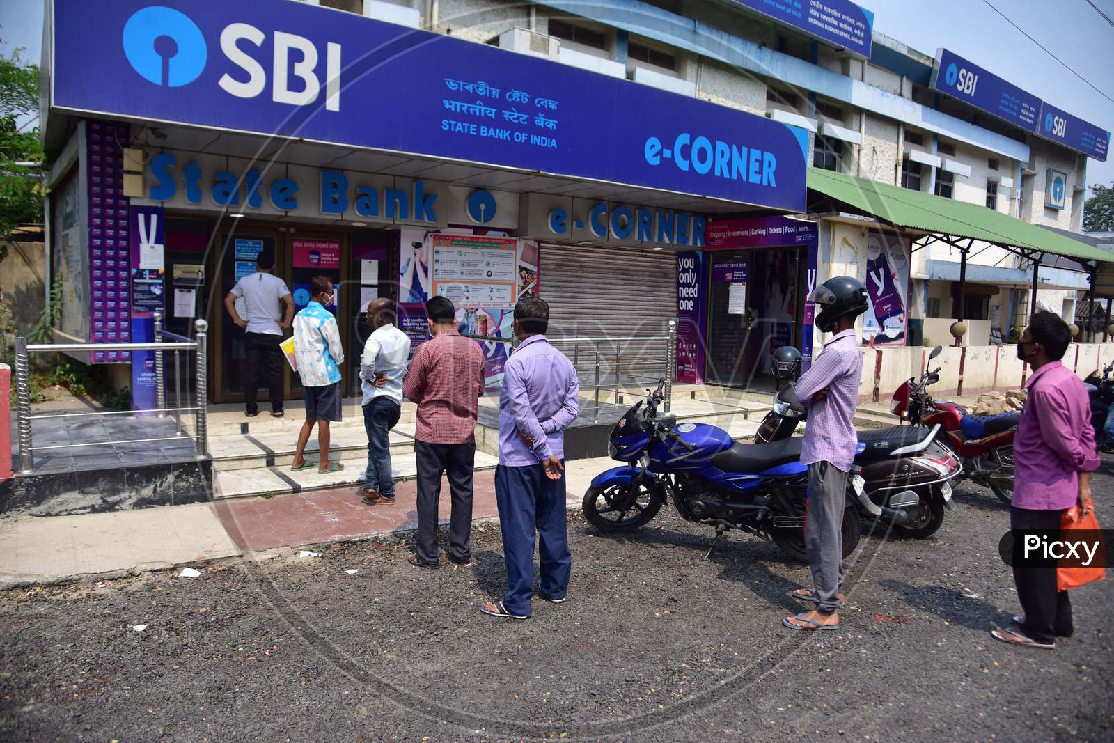 People  Standing At Safe Distances In A Queue Wait To Collect Money Outside Atm  During The Nationwide Lockdown Imposed In Wake Of Coronavirus Pandemic, In Nagaon District Of Assam ,India