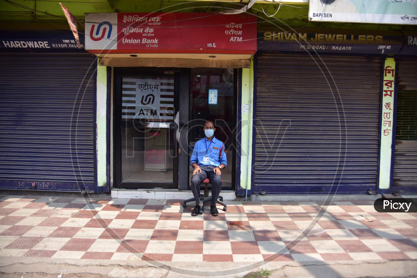 A Security Guard Wear Mask As He Sit Outside A Bank  Atm  During A Nationwide Lockdown In The Wake Of Coronavirus Pandemic, In Nagaon District Of Assam ,India