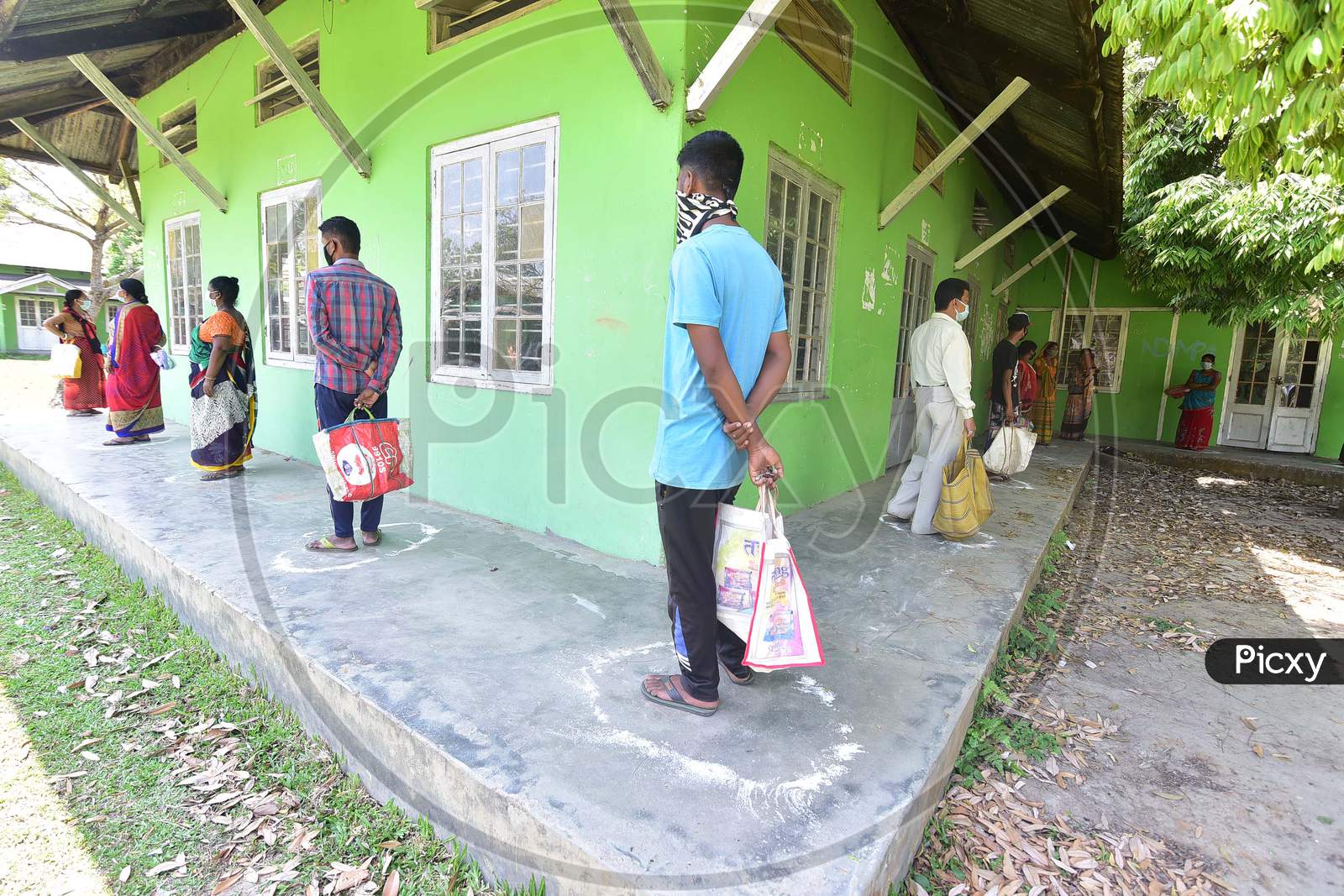 People Maintain Social Distance As They Wait In A Queue Wait To Collect Free Rice Being Distributed By The Government During The Nationwide Lockdown Imposed In Wake Of Coronavirus Pandemic, In Nagaon District Of Assam On April 04,2020