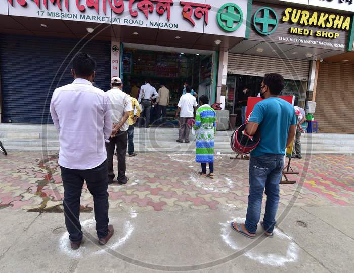 People Standing In Circles Drawn With Chalk To Maintain Safe Distance As They Wait To Enter A Medical  Shop During The Coronavirus Disease (Covid-19) Outbreak In Nagaon District Of Assam ,India
