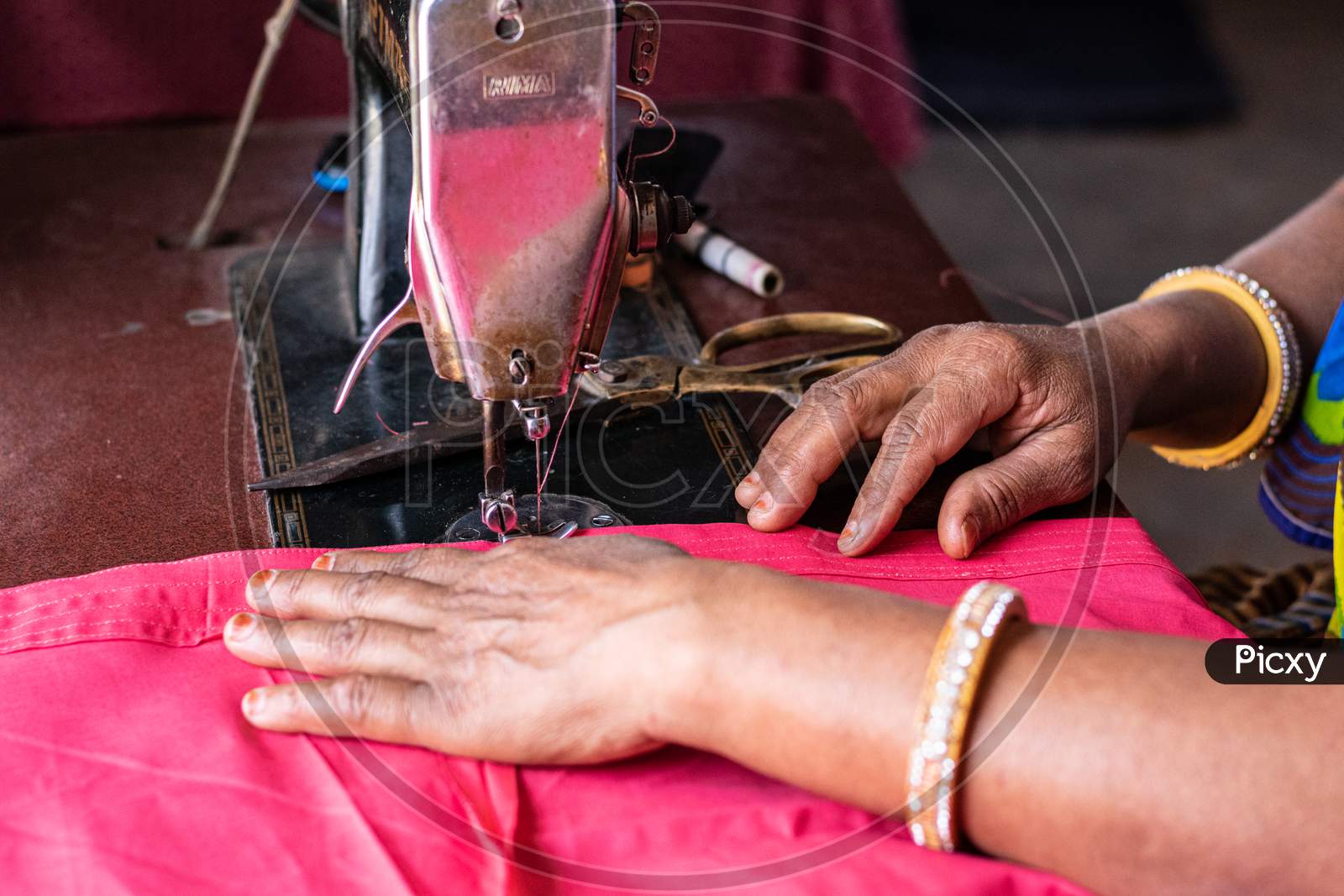A woman sewing clothes on sewing machine at home
