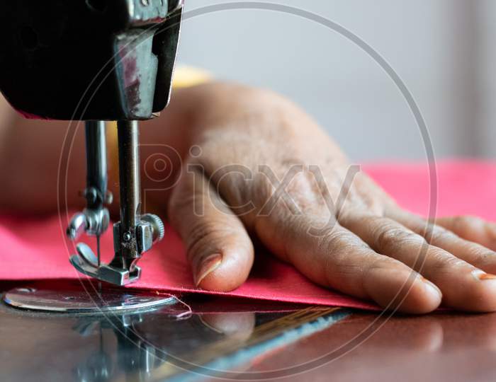 A woman sewing clothes on sewing machine at home closeup