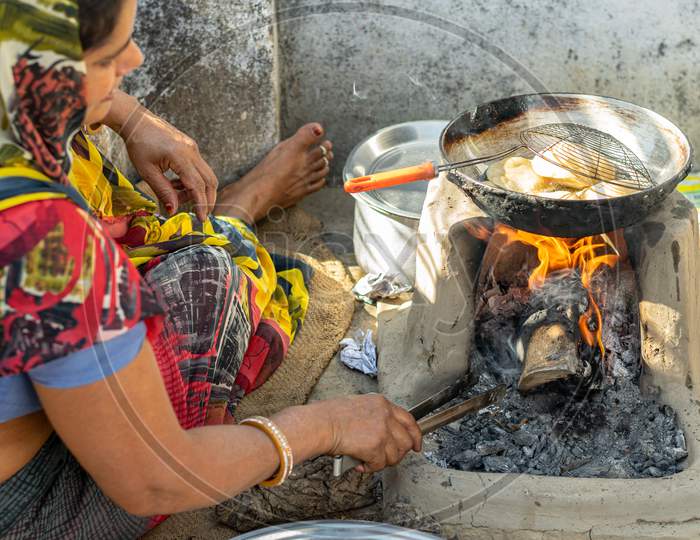 Deep fried Puris or Pooris are being prepared by a woman on traditional stove on the occasion of Navratri Pooja