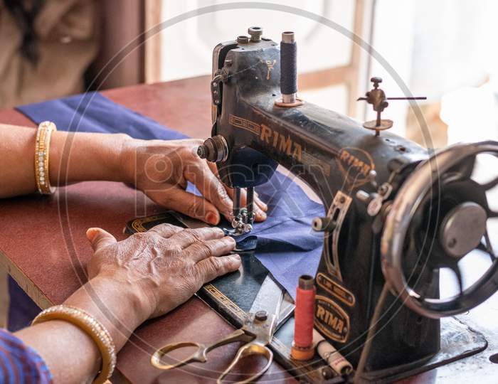 A woman sewing clothes on sewing machine at home