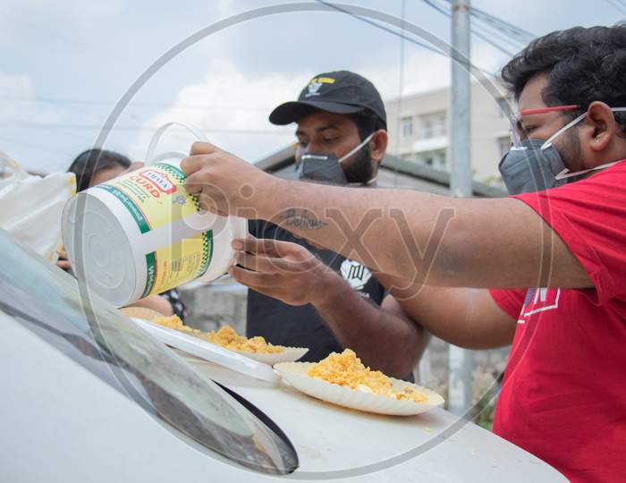 people putting food in plates to feed the stray dogs