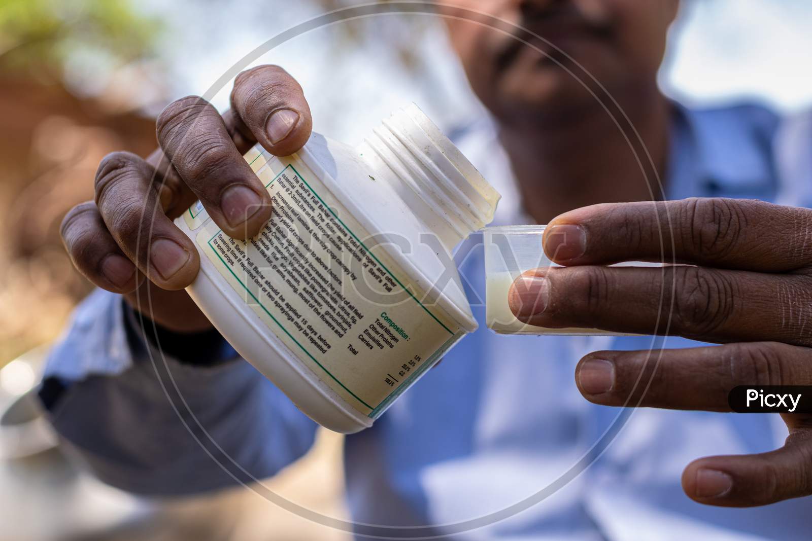 A farmer taking the pesticide into a measurement cup