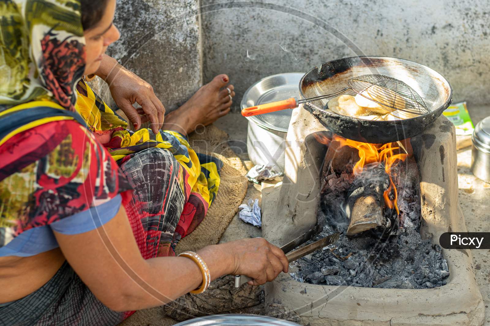 Deep fried Puris or Pooris are being prepared by a woman on traditional stove on the occasion of Navratri Pooja