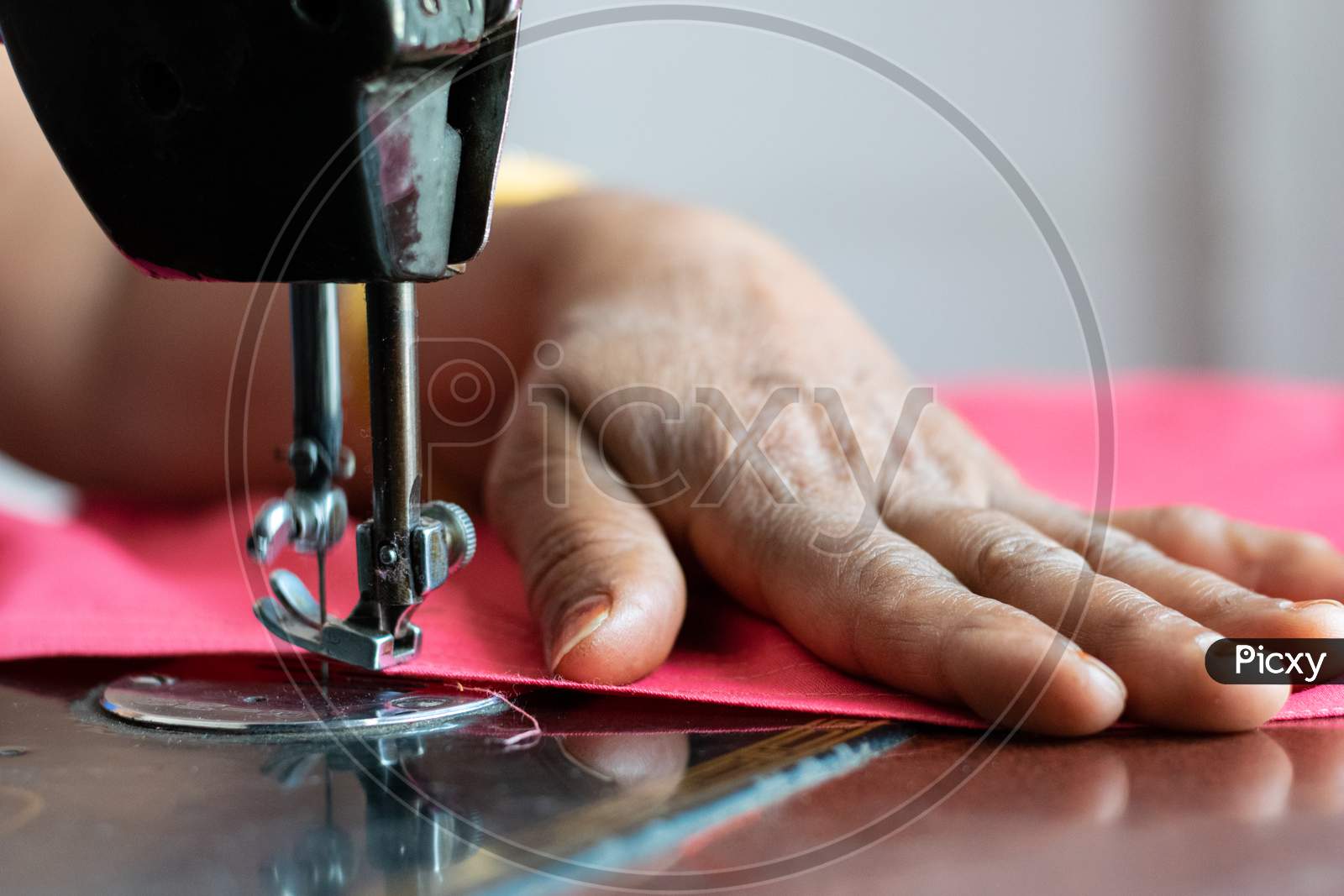 A woman sewing clothes on sewing machine at home closeup