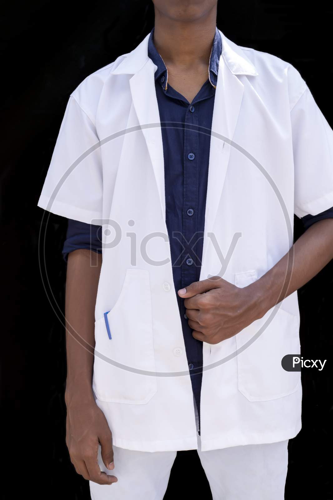 Cropped Portrait Of A Young Male Doctor With Hands Holding A White Coat On A Black Background
