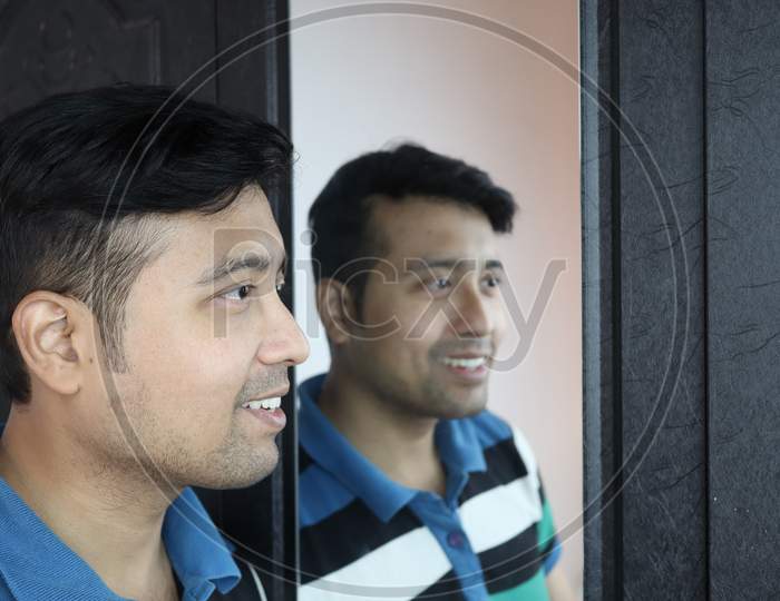 A Man And His Reflection In Mirror In Happy Mood.