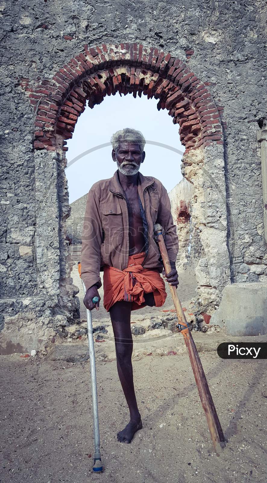 Dhanushkodi, India - 19 August 2018: An unknown physically challenged man standing in front of an abandoned church damaged by a super cyclone in 1964