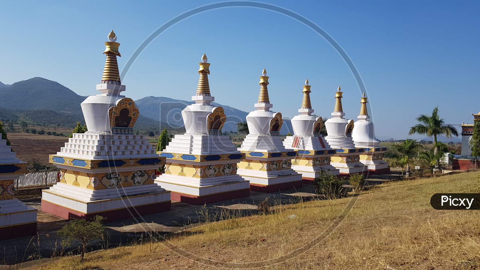Kollegal, Karnataka / India - March 14 2020: Beautiful wide angle view of the Stupas at the Dhondenling monastery on a bright day with the mountains in the background