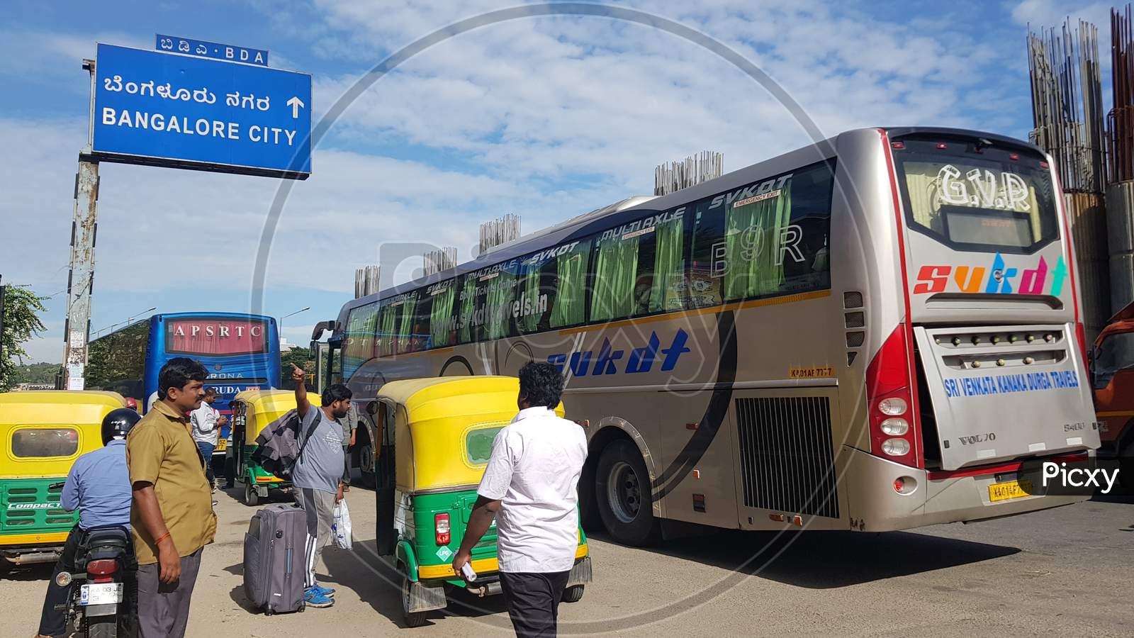 Bengaluru, Karnataka / India - August 08 2019: People alighting from an interstate bus at a busy road with a hoarding that has 'Bangalore City' written in Kannada text