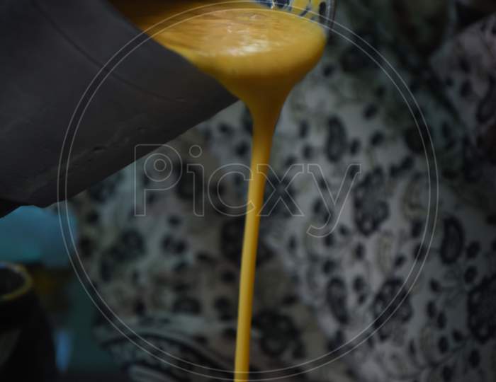 woman pouring mango shake into a glass
