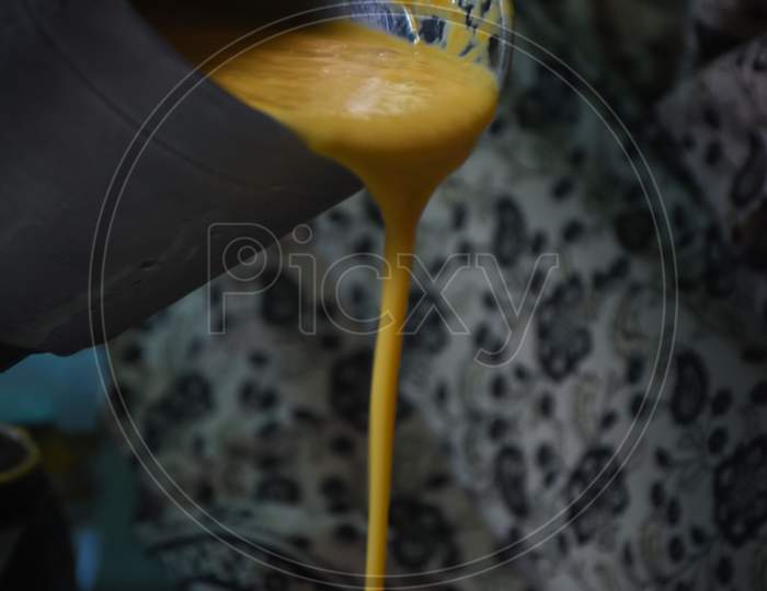 woman pouring mango shake into a glass
