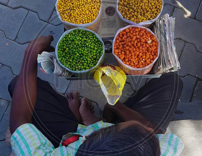 Bengaluru, Karnataka / India - September 01 2019: Looking down view of a man selling flavoured nuts on a footpath during daytime