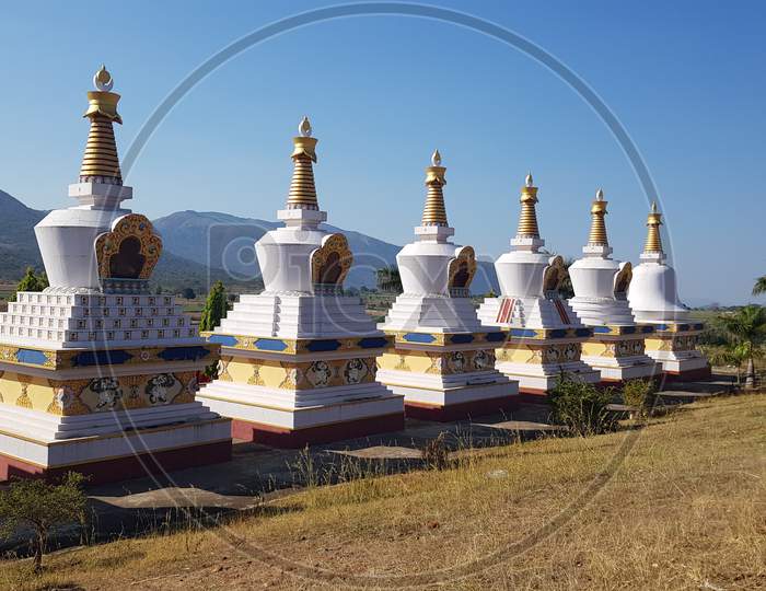 Kollegal, Karnataka / India - March 14 2020: Beautiful wide angle view of the Stupas at the Dhondenling monastery on a bright day with the mountains in the background