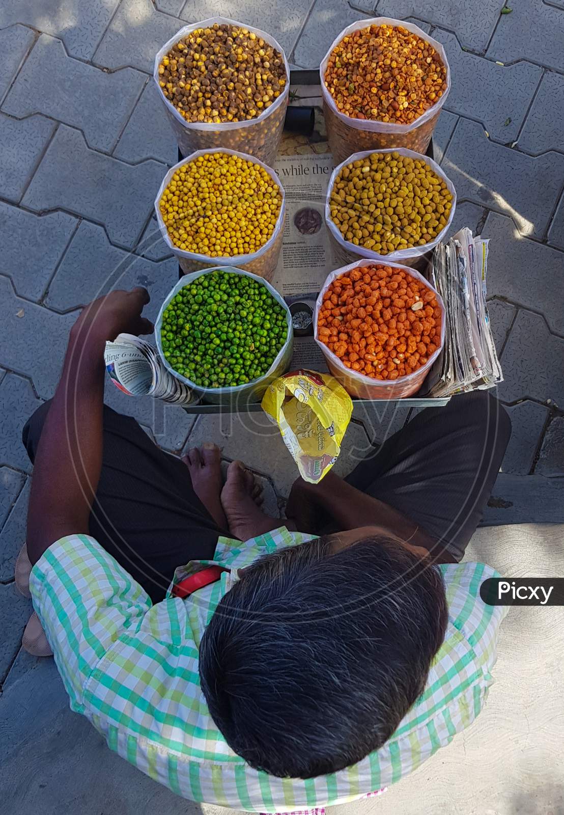 Bengaluru, Karnataka / India - September 01 2019: Looking down view of a man selling flavoured nuts on a footpath during daytime