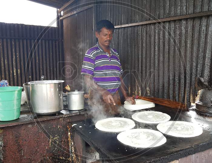Chennai, Tamilnadu, India - November 15 2019: A man making crispy piping hot 'Dosa'', the Indian version of pancake made with rice, in a road side shop
