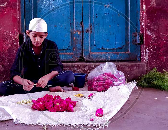 Bengaluru, Karnataka / India - July 01 2019: A young muslim boy selling flowers at Russel market.