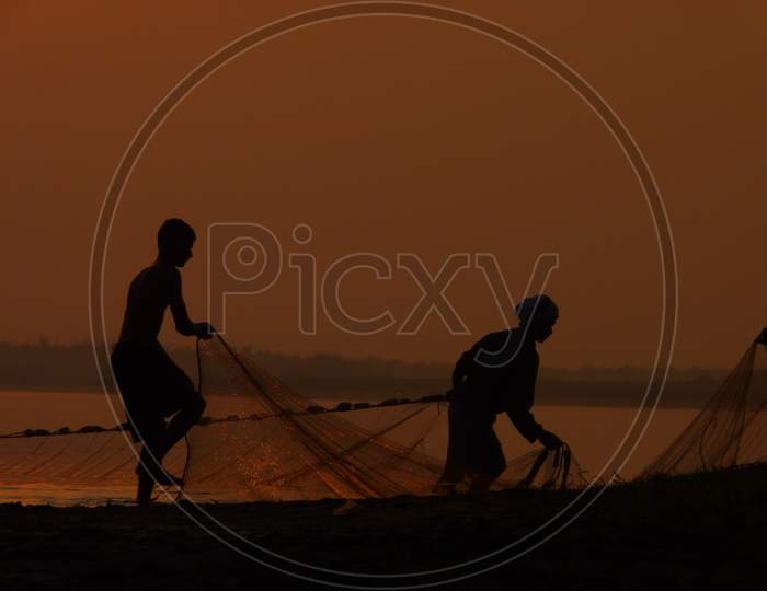 Fishermen preparing their fish nets at the sea shore in the early morning
