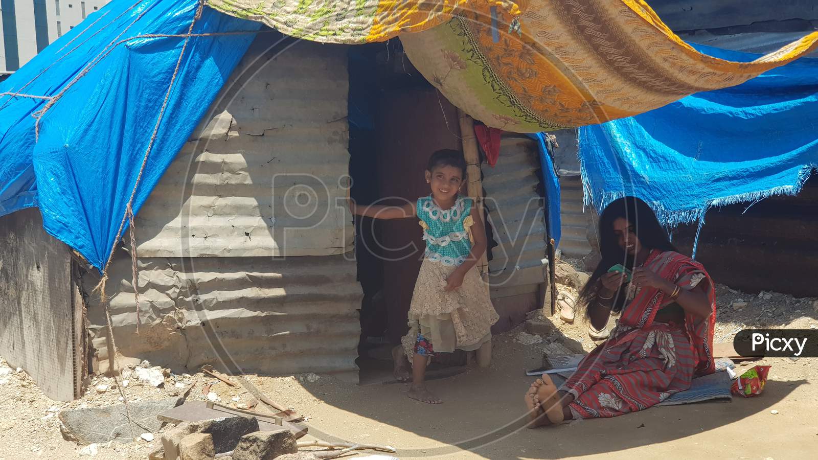 Bengaluru, Karnataka / India - August 20 2019: A mother and daughter in front of their shack in a slum during daytime