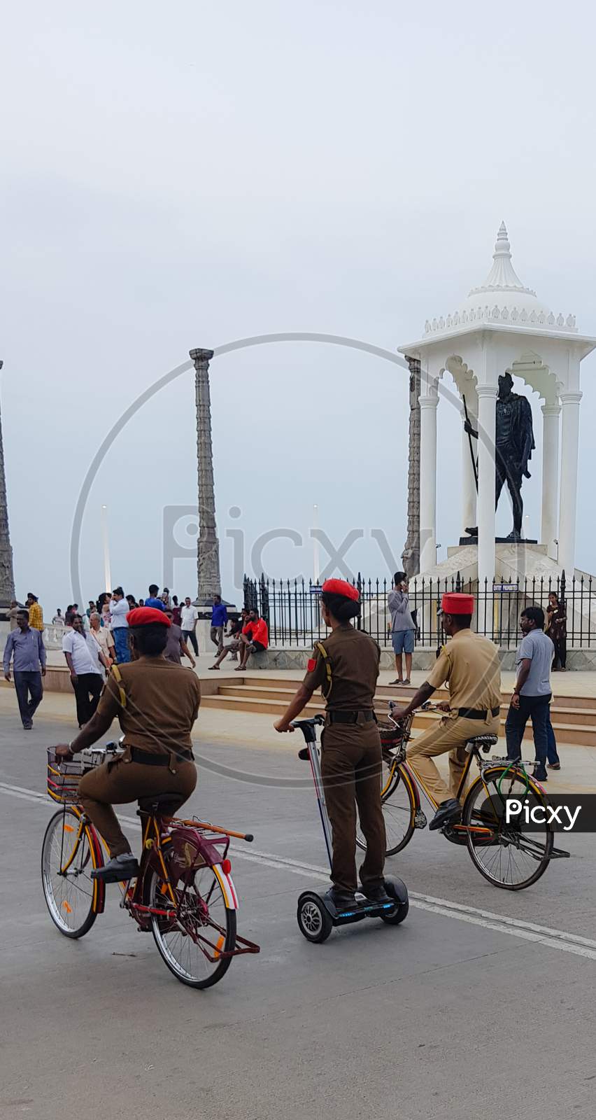 Pondicherry, India - 11 August 2018: A portrait photo of a cops riding bicycle and segway at a beach as a passerby and public look at them.