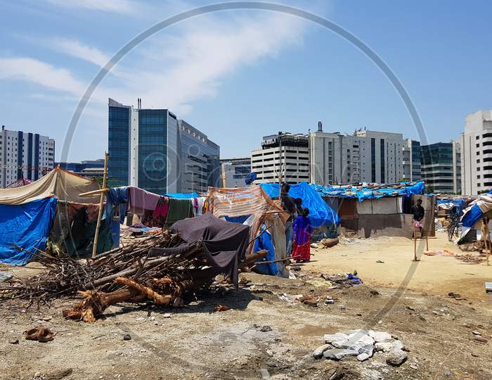 Bengaluru, Karnataka / India - August 02 2019: Wide angle view of a slum on a sunny day with multistorey corporate buildings in the background