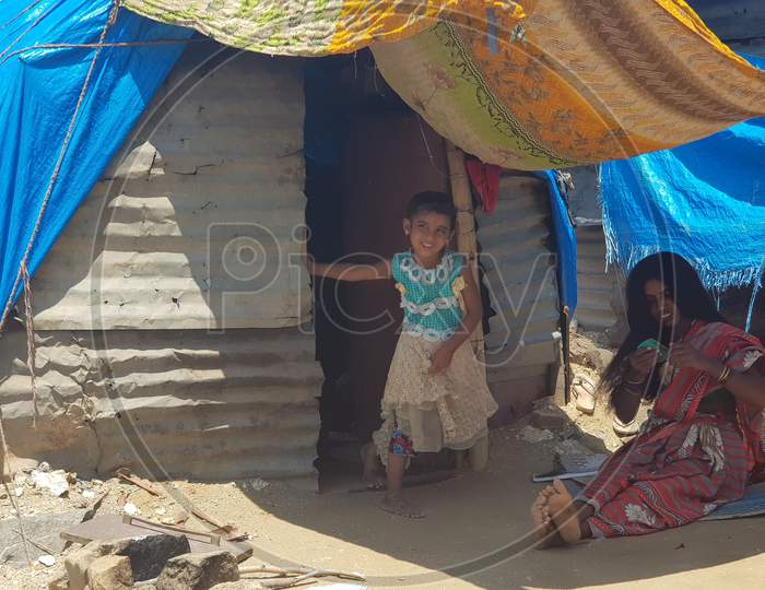 Bengaluru, Karnataka / India - August 20 2019: A mother and daughter in front of their shack in a slum during daytime