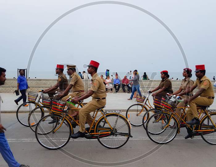 Pondicherry, India - 11 August 2018: A group of cops riding bicycle at a beach as a passerby and public look at them